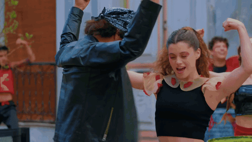 a woman in a black top is dancing with a man in a leather jacket
