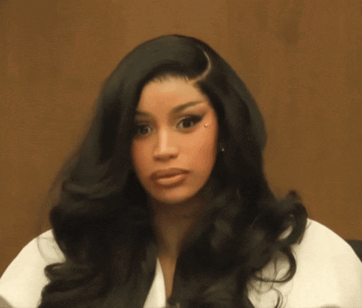Cardi B looks forward skeptically in a seated close-up.