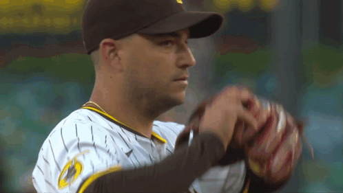 a baseball player wearing a brown hat and a white and yellow jersey