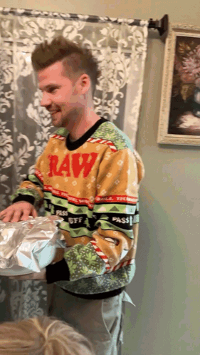 a man wearing a raw sweater is holding a gift