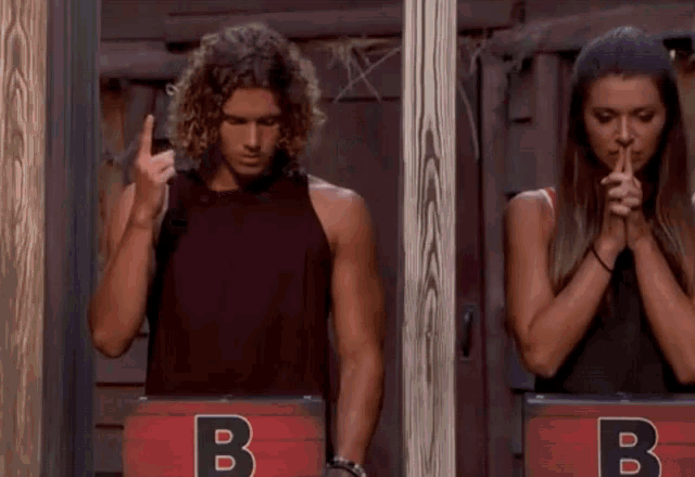 a man and a woman are standing in front of a sign that says b