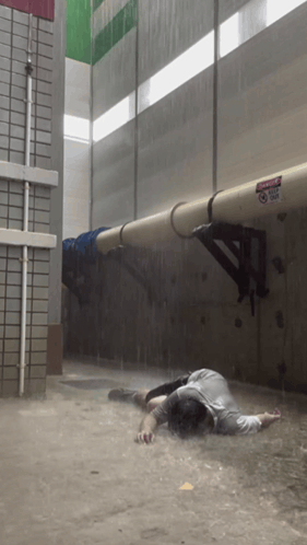 a man is laying in a flooded area with a sign on the wall that says danger do not enter