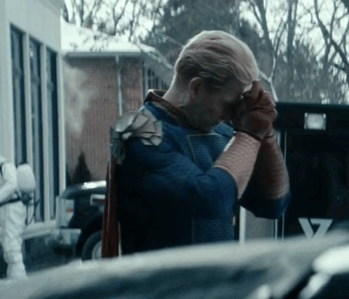 a man in a superhero costume is covering his face with his hand
