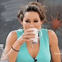 A woman sips a drink while suppressing laughter.