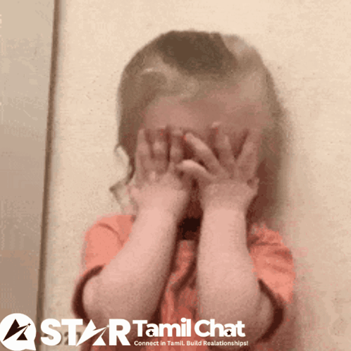 A small child hides their face behind both hands.