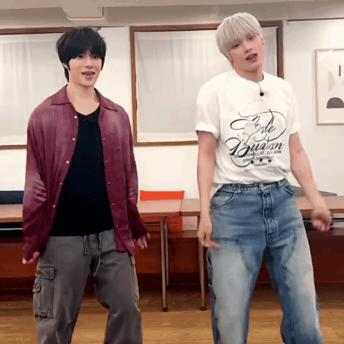 two men are dancing in a room and one has a white shirt that says " cafe illusion "