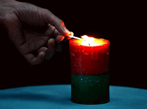 a person is lighting a red candle with a match