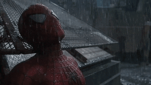 a spider man is standing in the rain looking up at something