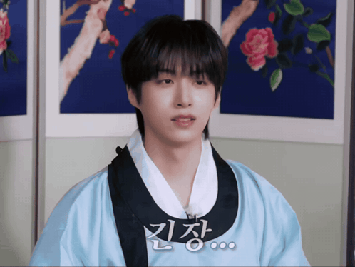 a young man wearing a blue kimono with chinese writing on the front