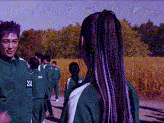 a group of people in green uniforms are standing in a field .