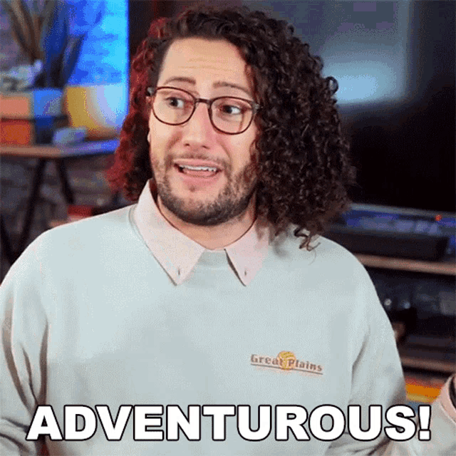 a man with curly hair is wearing glasses and a sweater that says great plains on it