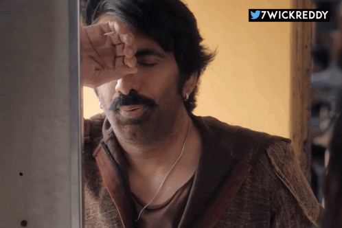 a man with a mustache is leaning against a wall with his hand on his forehead and the hashtag 7wickreddy above him