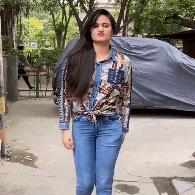 a woman wearing a denim shirt and jeans making a funny face
