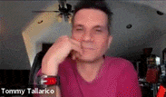 a man in a pink shirt is talking on a video call .