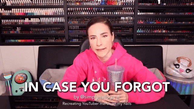 a woman in a pink hoodie says " in case you forgot " in front of a wall of nail polish
