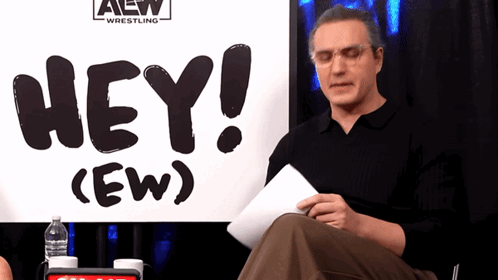 RJ City looks down at papers beside the “HEY! (EW)” sign.